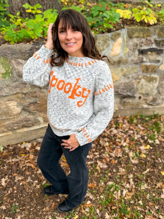 Model wearing a sweater with 'Spooky' text with orange stitching