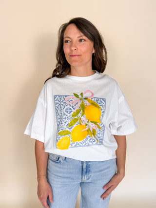 Woman wearing a white t-shirt with a lemon design on a beige background