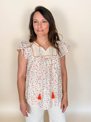 Cream floral embroidered boho top with crochet lace yoke and tassel tie neckline.