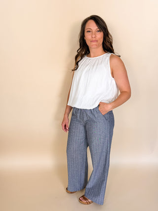 Woman wearing a white top and blue checkered pants against a beige background