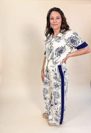 Woman wearing a white outfit with blue floral patterns on a beige background