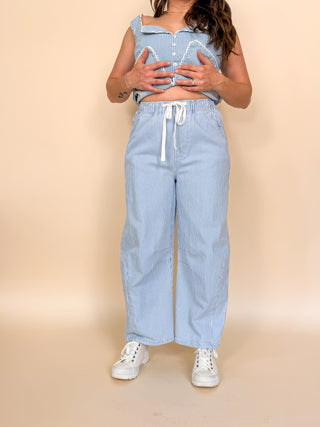 Person wearing a blue striped outfit with white sneakers on a beige background