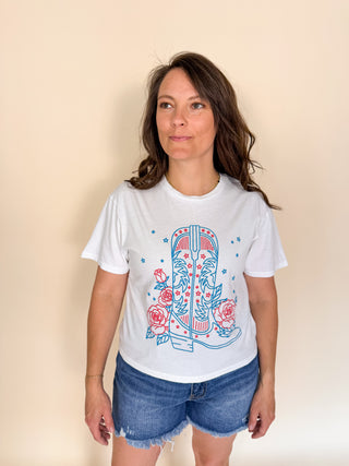Woman wearing a white t-shirt with a colorful boot design on a beige background