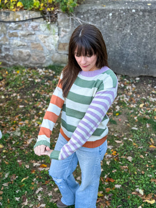 Woman wearing a colorful striped colorblock sweater standing outdoors 