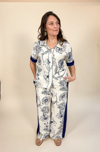 Woman wearing a floral pajama set with blue accents on a beige background