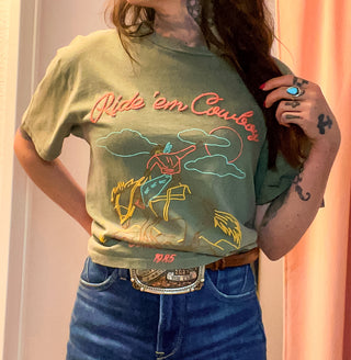 Person wearing a green t-shirt with 'Ride 'em Cowboys' graphic design.