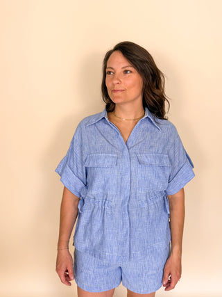 Woman wearing a blue chambray matching set against a beige background