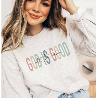 Heather grey graphic crew sweatshirt reading “God Is Good All the Time” in soft multicolor lettering.